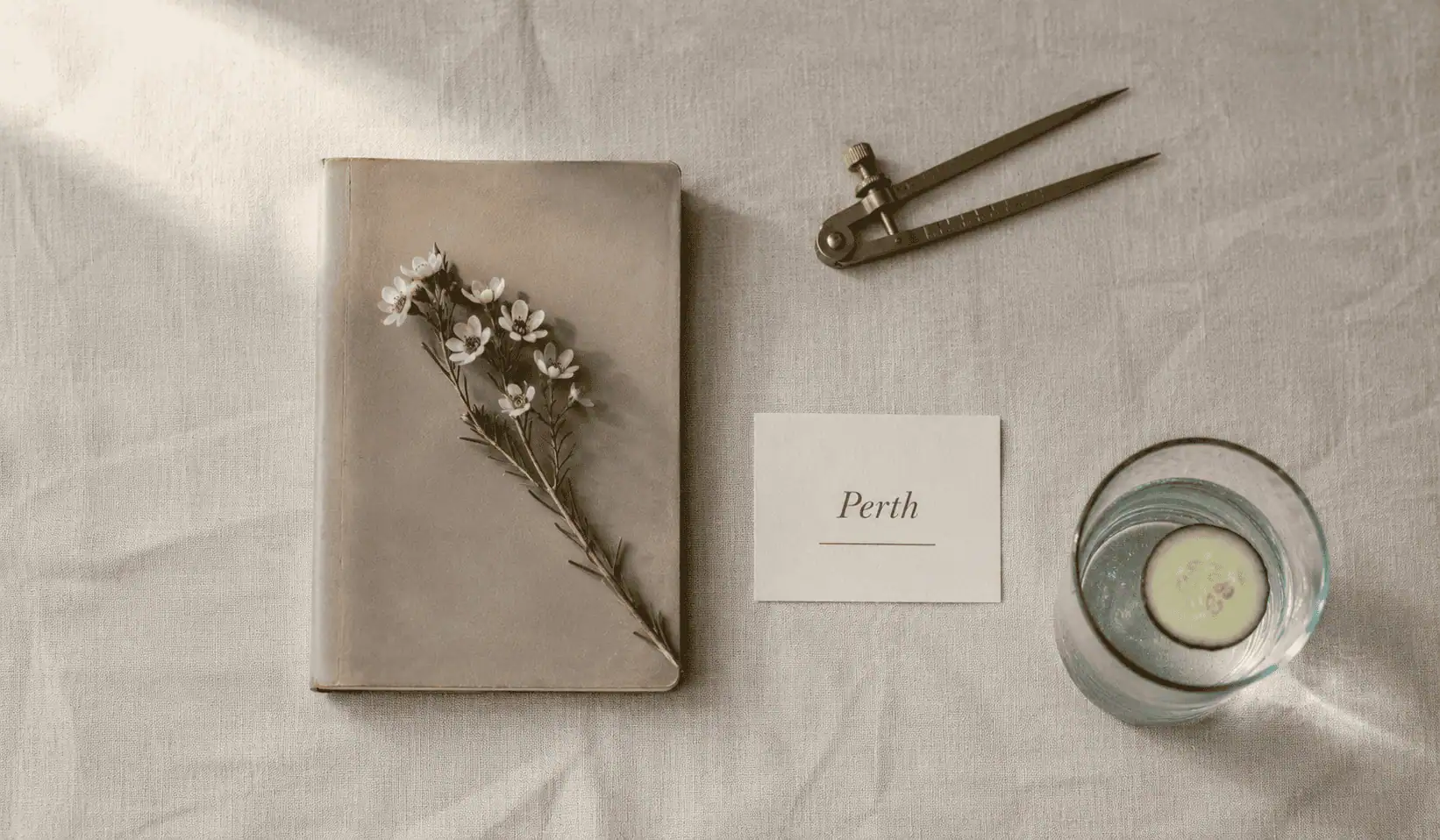 Perth anaesthetic billing service — editorial still life of a closed leather logbook with a brass key resting on the cover, a half-drunk espresso cup, and a small card reading Perth, on warm linen.
